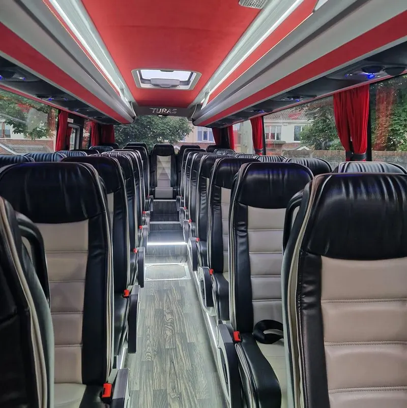 Coach interior with rows of black seats and red curtains
