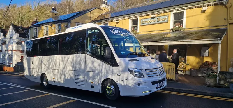 White mini coach parked beside a shop